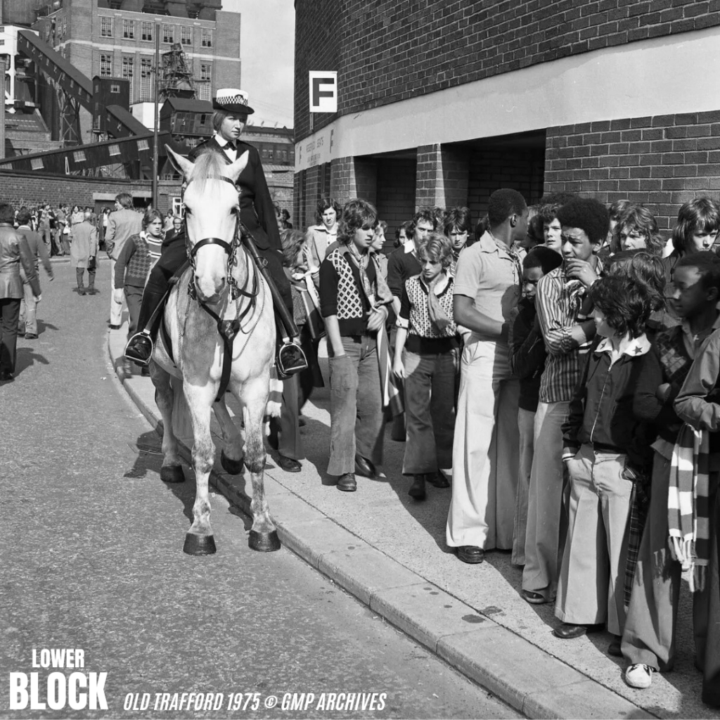 Old Trafford, 1975: Manchester United fans in flares, big collars, scarves, boots and sharp ’70s cuts queue for the Stretford End - admission 65p - as mounted police keep order.