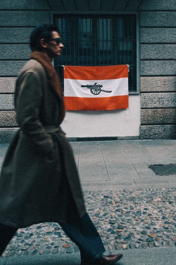 local Italian man walking past one of many Arsenal flags. Inter Milan away